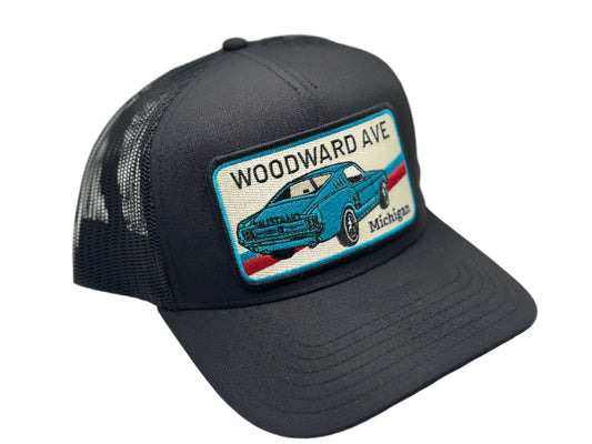 Black trucker hat with a patch featuring a blue car and 'Woodward Ave, Michigan' text on a white background.